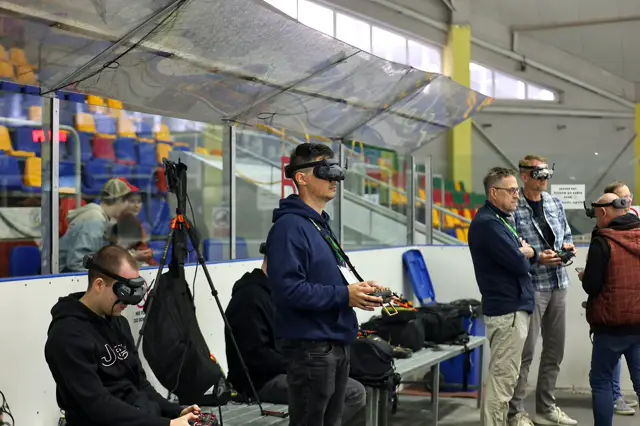 Piloci FPV w goglach przy torze na lodowisku