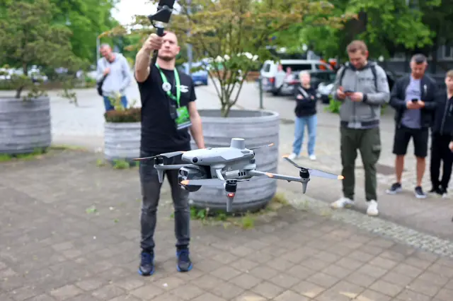 Pilot startuje dużym dronem przed halą